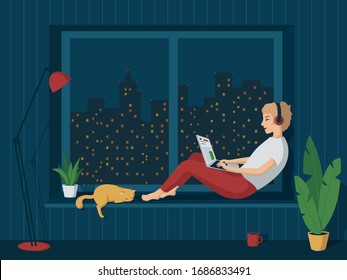 Young happy girl in home clothes is sitting at the window with a laptop in headphones. Night city outside the window. Remote work from home. Freelance. Learning on the Internet. Online Store Shopping