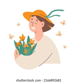 Young happy woman in a hat smiling and holding flowers