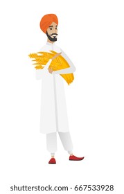 Young hindu farmer in headscarf holding hay in hands. Full length of smiling farmer with hay in hands. Farmer carrying hay. Vector flat design illustration isolated on white background.