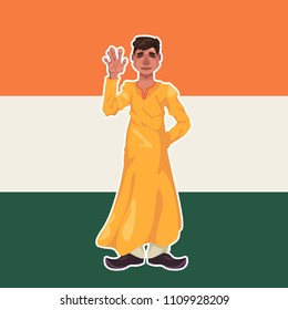A young Indian guy dressed in lungi clothes stands on the background of the Indian flag and waves his hand