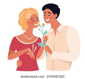 Young lovers are sniffing a flower, a guy hugs a girl by waist, she has a ring on her hand, they are betrothal.