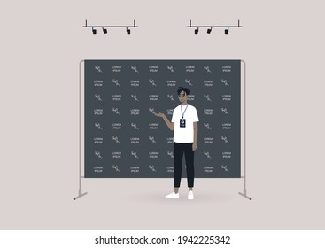 Un joven personaje negro parado frente a un fondo negro de pared de prensa cubierto con un patrón de logo, un evento de conferencia de prensa