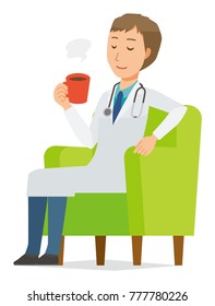 A young male doctor wearing a white suit sits on a sofa and is drinking coffee