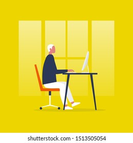 Young male manager sitting at the computer. Office worker. Interior. Desk and chair. Side view. Millennial lifestyle, daily routine.