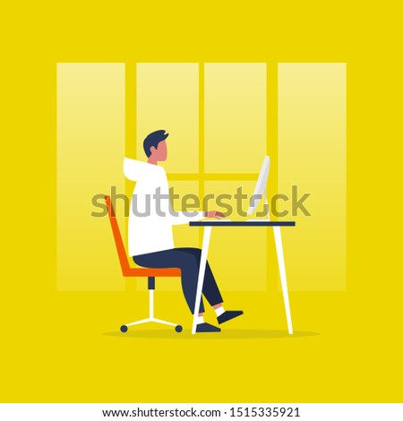 Young male manager sitting at the computer. Office worker. Interior. Desk and chair. Side view. Millennial lifestyle, daily routine.