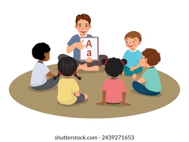 Young male teacher explaining and showing alphabet letters to students sitting on floor