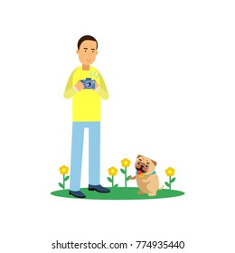 Young man character taking photo of his cute pug dog on a green lawn with flowers. Boy enjoys photography. Flat vector cartoon illustration