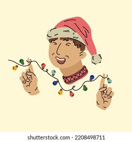 A young man in a Christmas hat smiles and holds a garland in his hands A man celebrating Christmas.