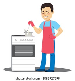 Young man cooking soup on electric kitchen stirring pot with ladle