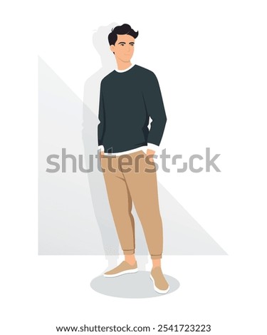 A young man in a dark gray sweater and light brown trousers stands in a relaxed pose.