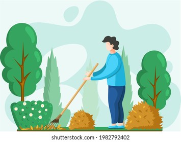Young man doing seasonal garden work, remove leaves with rake, works on yard with trees. Agricultural worker in autumn tidies up garden, removes fallen yellow leaves stands near trees and bushes