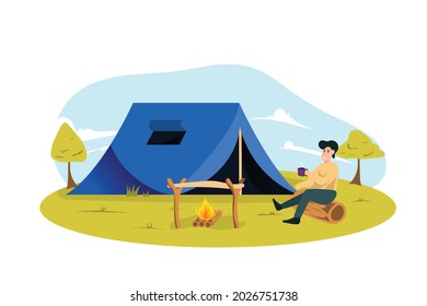 A young man drinking coffee enjoying a campfire while camping