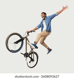  A young man excitedly jumping  on top  with bicycle.  just one wheeled up and back wheeled  touch in  road. watching lot of people standing on road.