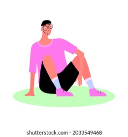 A young man in glasses, a T-shirt and shorts is sitting on the grass. Modern youth fashion. Isolated vector illustration. Free style. Casual clothing. Relaxed posture.