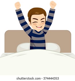 Young man happy waking up sitting on bed with arms up