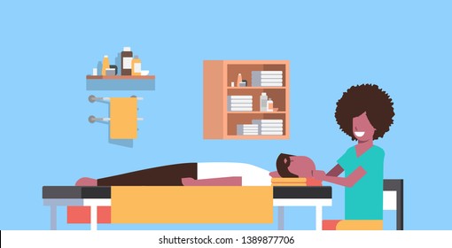 young man having head massage african american masseuse massaging patient body guy relaxing lying on table luxury spa salon treatments concept horizontal