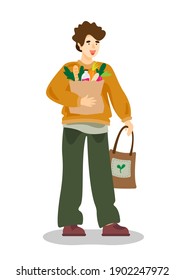 Young man holding a grocery paper bag and eco bag. Man with shopping bags. Zero waste, vegetarianism, ecology. No plastic bags. Eco bag with vegetables.