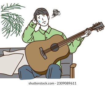 Young man holding a guitar while holding his head
