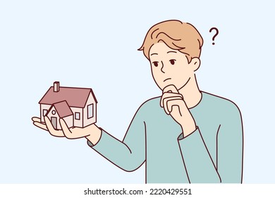 Young man holding house thinking of mortgage or loan. Confused male with home maquette frustrated with housing rent or purchase. Real estate agent. Vector illustration. 