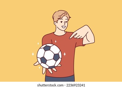 Young man holds out hand with soccer ball and points finger at it offering to play football. Guy teenager wants to lead active lifestyle compete in team sports. Flat vector illustration
