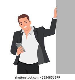 Young man leaning against a grey wall using mobile phone with copy space. Happy casual guy messaging on smartphone on gray background. Cheerful man typing and reading a message on cell phone.