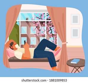 Young man lying on windowsill at home serfing internet with phone. Male character resting in room near big window with spring cityscape view. Spending time at home, relaxing after work, reading