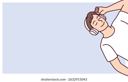 Young man lying peacefully with closed eyes and headphones, relaxing while listening to music, placed on pastel blue banner with empty space for design or messaging copy space