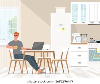 A Young Man In Pajamas With A Cup Works At A Computer In The Kitchen.