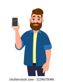 Young man showing blank screen smartphone in hand. Mobile phone 
app or application and cellphone communication technology concept illustration in vector cartoon style.