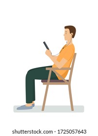 A young man sits sideways in a chair and looks at a tablet. A person with headphones, listening to music or reading. Flat vector illustration.