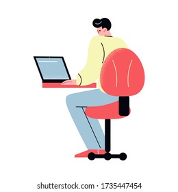 Young man sitting and doing computer work in office, rear vire