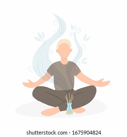 Young man sitting in lotus pose with aroma diffuser. Aromatherapy and relax. Self care at home.