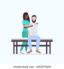 young man sitting on bed african american masseuse therapist in uniform doing healing treatment massaging patient body manual therapy physiotherapy concept