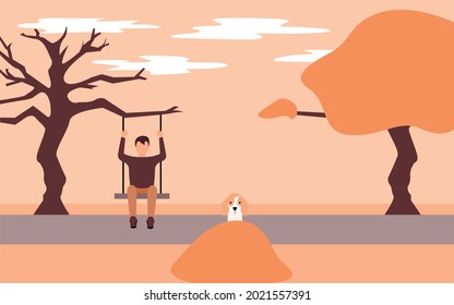 Young man sitting on a swing attached to a tree and his dog playing on a mound of leaves