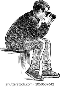 A young man sitting and taking picture