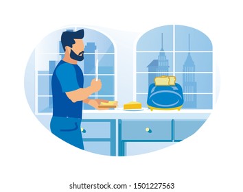 Young Man, Spreading Butter on Toast, in His Home Kitchen, with Cabinets, Toaster and Plate with Dairy Butter, Holding Knife in His Right Hand, With Outline of Big City and Skyscrapers Outside