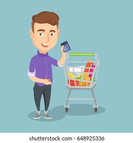 Young man standing near the supermarket trolley full of products and holding a calculator in hand. Caucasian man checking prices with a calculator. Vector flat design illustration. Square layout.