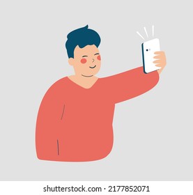 Young man taking selfie photo with his smartphone. Teenage boy addicted to social media and has a video call with his virtual friends. Concept of phone conversation and long distance relationships.
