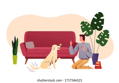 Young man is training a dog in the living room. Man spends time with his pet at home. People and home daily activities