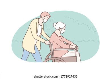 Young man volunteer in medical face mask pushing wheelchair old woman granny pensioner. Social support and helping senior citizen