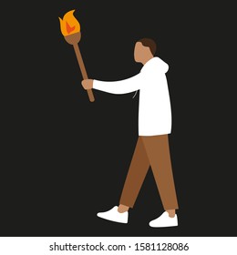 A young man walks in the dark with a torch in his hand
