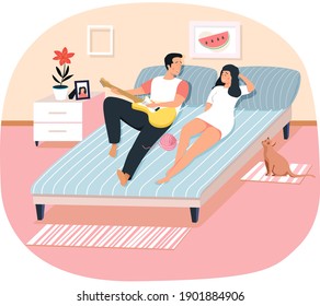 Young people spend free time at home, man plays guitar for woman couple lying on bed, cat is sitting next to. Romantic evening for two, guy singing songs for his wife in bedroom, people are resting