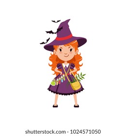 Young red-haired girl witch standing with arms akimbo. Kid character in costume, bag with herbs and belt with potions, purple dress and hat. Flat cartoon vector on white.