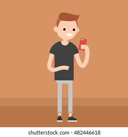 Young redhead guy is looking at his smart phone's screen / editable flat vector illustration