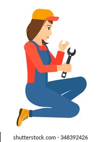 Young repairer sitting with a spanner in hand vector flat design illustration isolated on white background. Vertical layout.