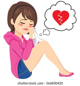 Young sad woman crying sitting on floor with broken heart on speech balloon