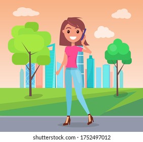 Young smiling girl wearing pink t-shirt and jeans, stylish shoes at heels. Fashionable woman with bob hairstyle walking in green park at urban view background. Cheerful girl posing, talking by phone