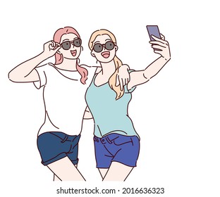 Young smiling hipster women in trendy summer t-shirt clothes, they hugging and taking selfie. Hand drawn in thin line style, vector illustrations.