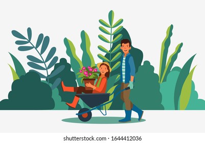 Young and smiling man pushing his laughing girlfriend in a wheelbarrow. Summer landscape background. Eco friendly ecology concept