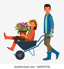 Young and smiling man pushing his laughing girlfriend in a wheelbarrow